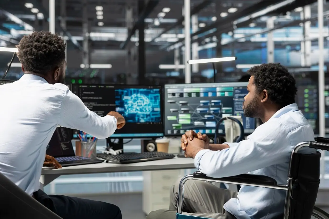 Менеджер серверной и сотрудник в инвалидном кресле используют искусственный интеллект.